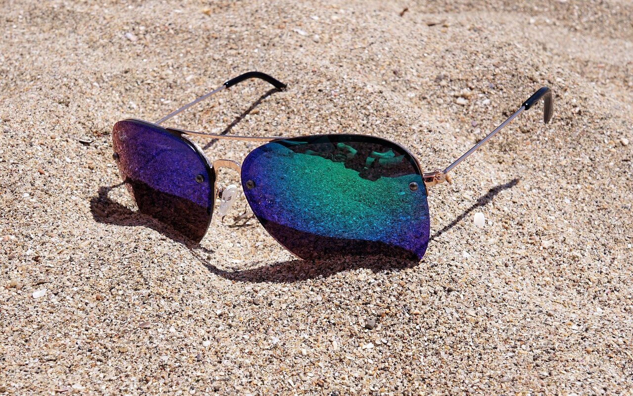 Lunettes de soleil posées sur le sable de la plage