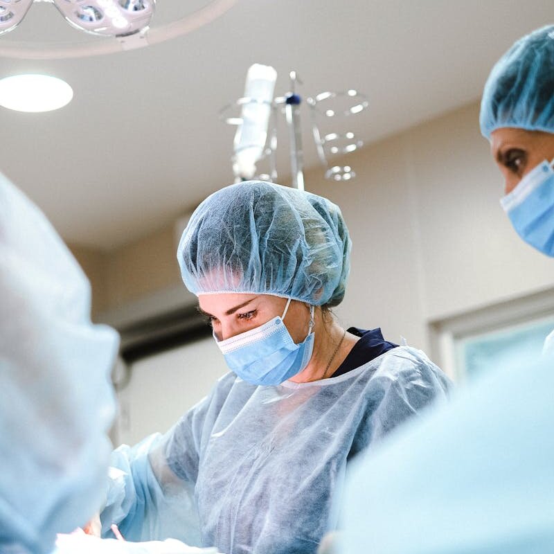 A team of surgeons and nurses in protective gear performing an operation in a hospital.