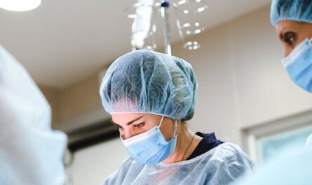 A team of surgeons and nurses in protective gear performing an operation in a hospital.