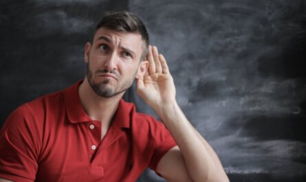 Thoughtful man listening intently against a chalkboard background in a red polo shirt.