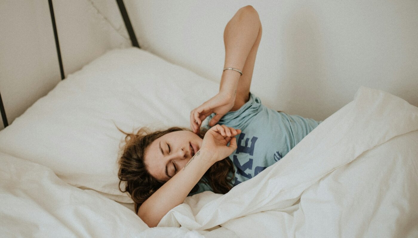 woman covered in white blanket sleeping on white bed comforter